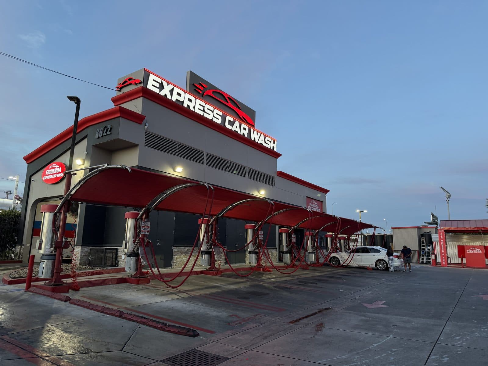 Exterior of the Figueroa Express Car Wash building with red canopies, vacuum stations, and blue California sky